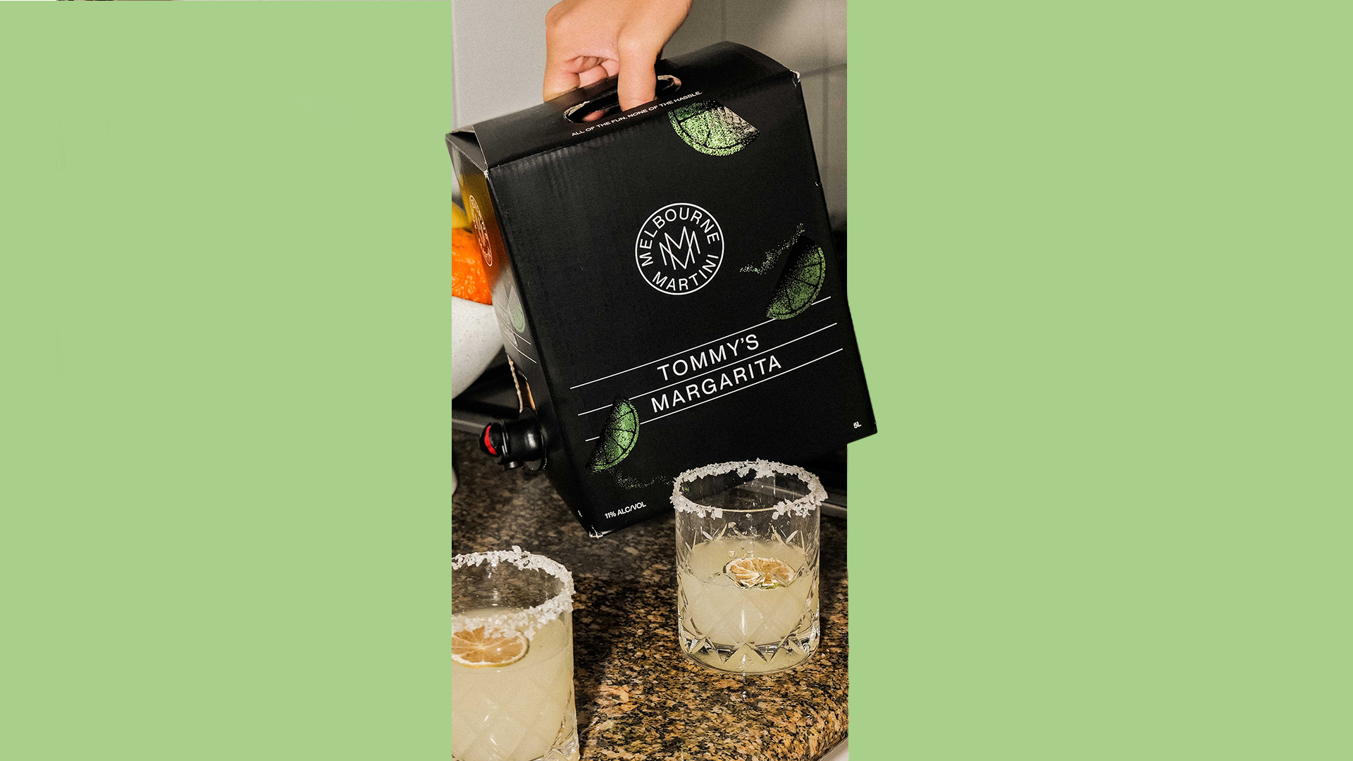 Tommy's Margarita Cask with two glasses of margaritas on a countertop.